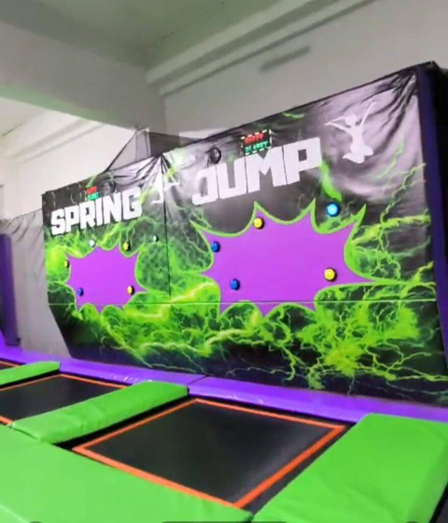 Zona de camas elásticas Spring Jump con pared de juegos y trampolines verdes y morados